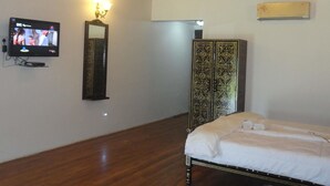 Quarto com cama, televisão, espelho fixado na parede e guarda-roupa.