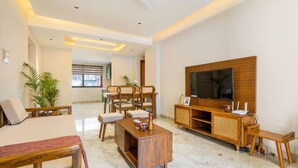 Un salón amplio con un televisor de pantalla plana grande, muebles de madera y piso de mármol.