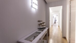 Um corredor com uma vitrine de vidro contendo sapatos, uma placa na parede e piso de madeira.