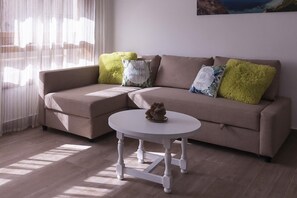 A modern living room with a beige sofa, a white coffee table, and decorative pillows. - Tropicana Apartment – 30m from the Beach with Park (Tossa De Mar)
