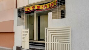 A building entrance with a decorative banner, a set of steps leading up to the door, and a gated entrance. - Townhouse Ganesh Tekdi Temple Nagpur (Nagpur)