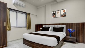 A modern bedroom with a large bed, a nightstand, a window with curtains, and wall art. - Townhouse Ganesh Tekdi Temple Nagpur (Nagpur)