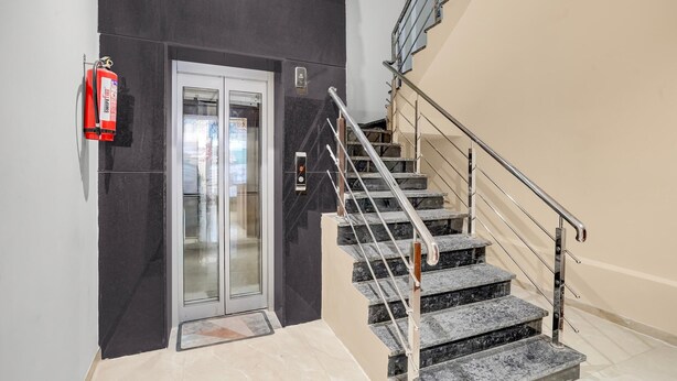 A staircase with metal railings, a fire extinguisher mounted on the wall, and a door with a glass panel. - Townhouse Ganesh Tekdi Temple Nagpur (Nagpur)
