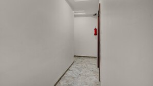 A narrow hallway with white walls, a marble floor, and a ceiling light. - Townhouse Ganesh Tekdi Temple Nagpur (Nagpur)