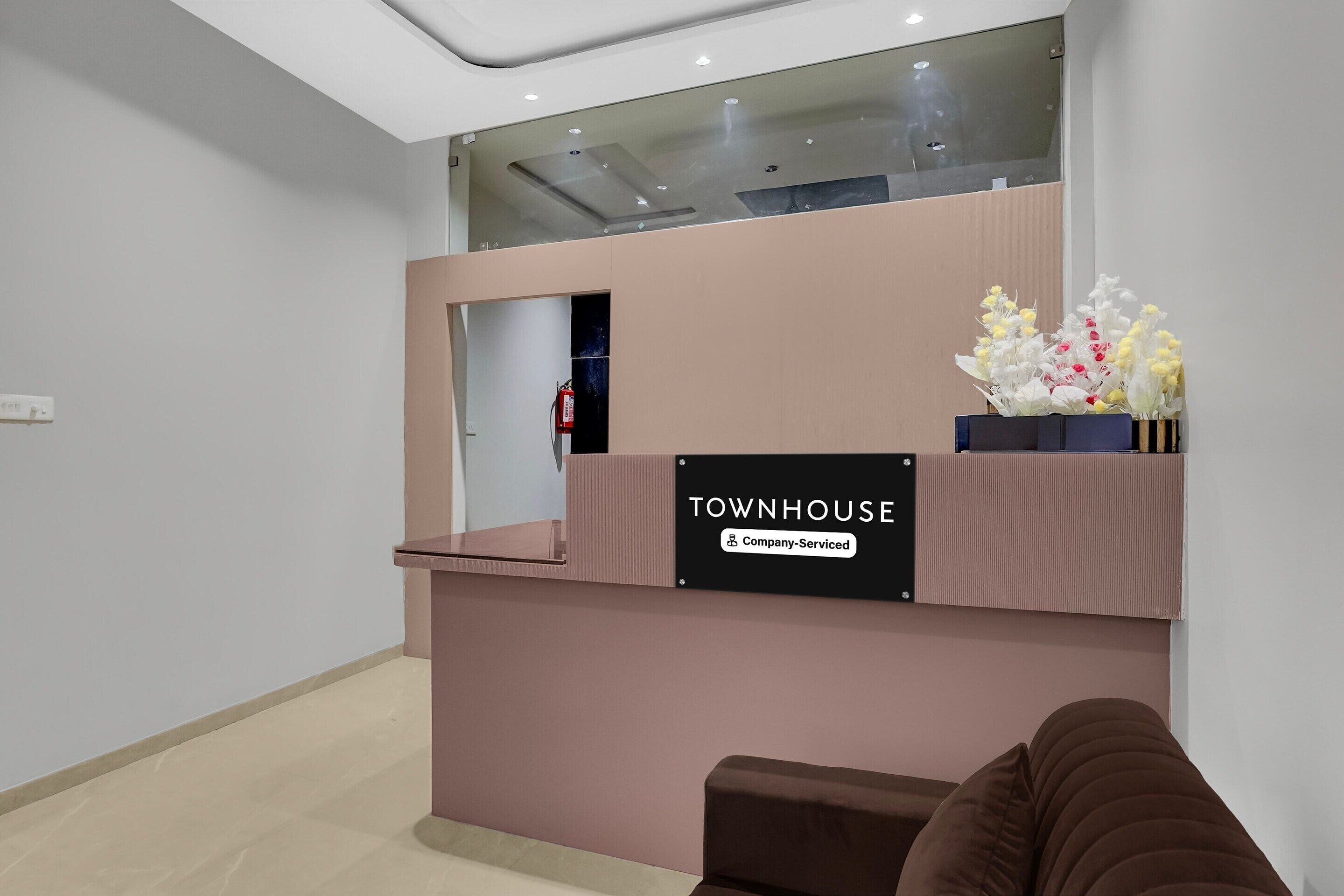 A reception desk with a sign reading 'TOWNHOUSE' and a fire extinguisher mounted on the wall.