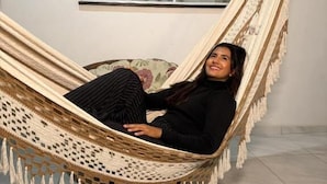 A person lying in a hammock in a room with a tiled floor and a window with curtains. - Pousada Cajueiro Do Sol (Barreirinhas)
