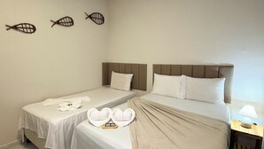 A hotel room with two beds, a bedside table with a lamp, and a woven basket on the floor. - Pousada Cajueiro Do Sol (Barreirinhas)