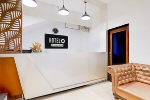 A hotel reception desk with a sign, a clock, and a brown leather sofa. - Super Itwari Station Formerl Hotel Prime (Nagpur)