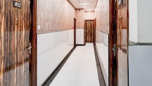 Ein Hotelkorridor mit Holztüren, die mit 102 und 107 gekennzeichnet sind, mit hellen Fliesenböden und einer zentralen Diele.