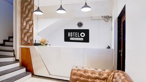 Ein Empfangsbereich mit einem 'HOTEL'-Schild, einer Treppe, einer gepolsterten Sitzecke und Pendelleuchten.