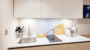 A kitchen with a sink, a toaster, and a cutting board. - 108 Shirland Road (London)
