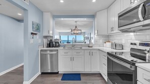 Una cocina moderna con armarios blancos, electrodomésticos de acero inoxidable y una pared decorada en azul.