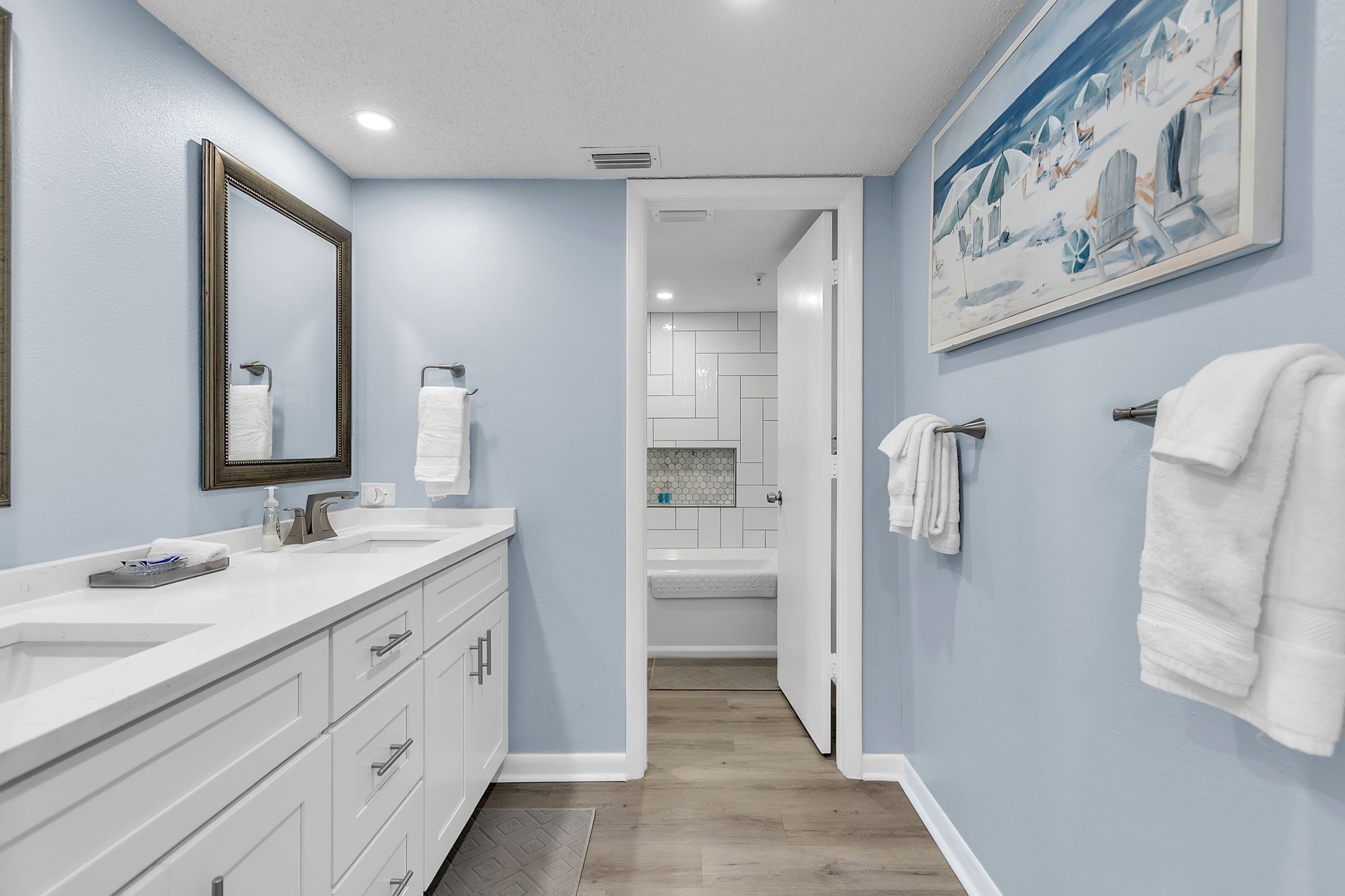 Une salle de bain avec un grand miroir, deux lavabos, une baignoire et une douche.