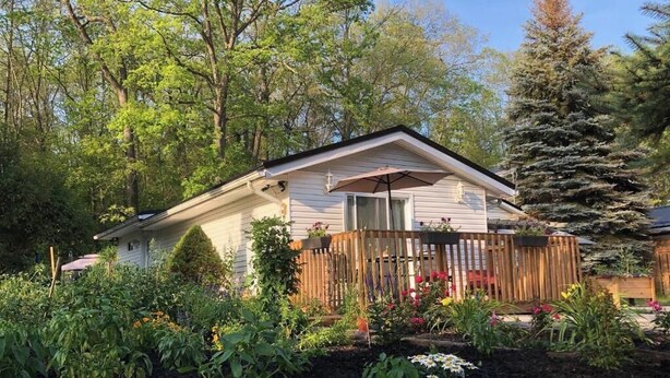 A house with a fenced backyard, surrounded by trees and a garden.
