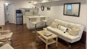 A modern living area with a sofa, coffee table, and a dining area with chairs.