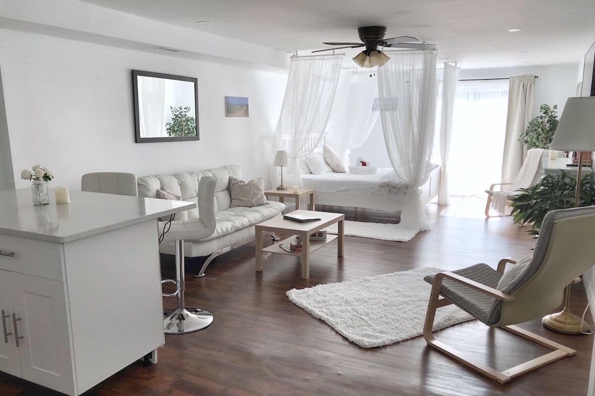 A modern living room with a sofa, armchair, coffee table, and a white cabinet.