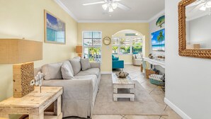 A living room with a sofa, coffee table, and a ceiling fan. - 🏖️2 Min Walk to Beach🌊Prime Location☀Barefoot Beach Resort E206 (Indian Shores)