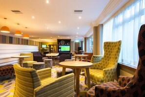 A hotel lobby with seating areas, a television, and a bar. - Holiday Inn Chester - South (Chester)