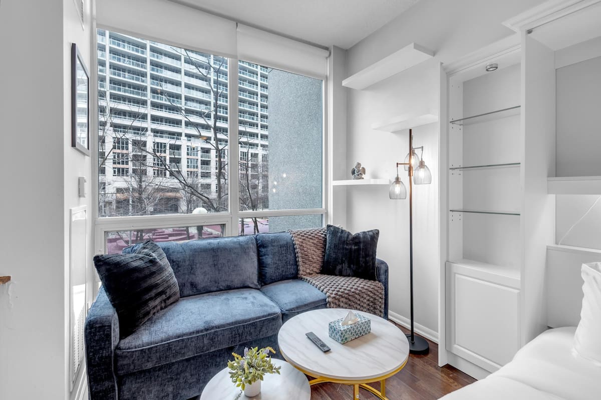 A modern living room with a sofa, a coffee table, and a view of a high-rise building.