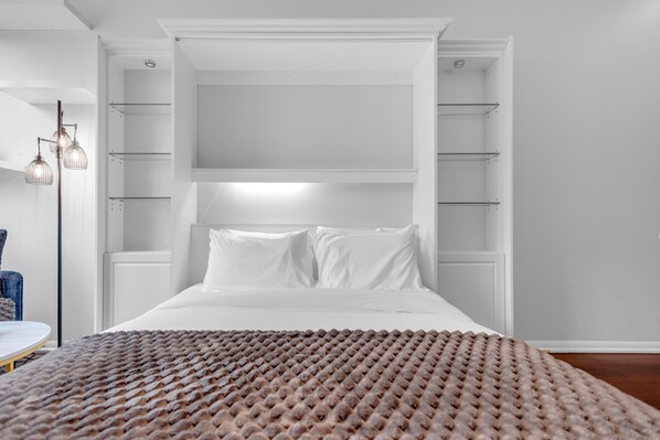 A modern bedroom with a large bed, built-in shelving, and a hanging light fixture. - The Bayview - Downtown Toronto (Toronto)