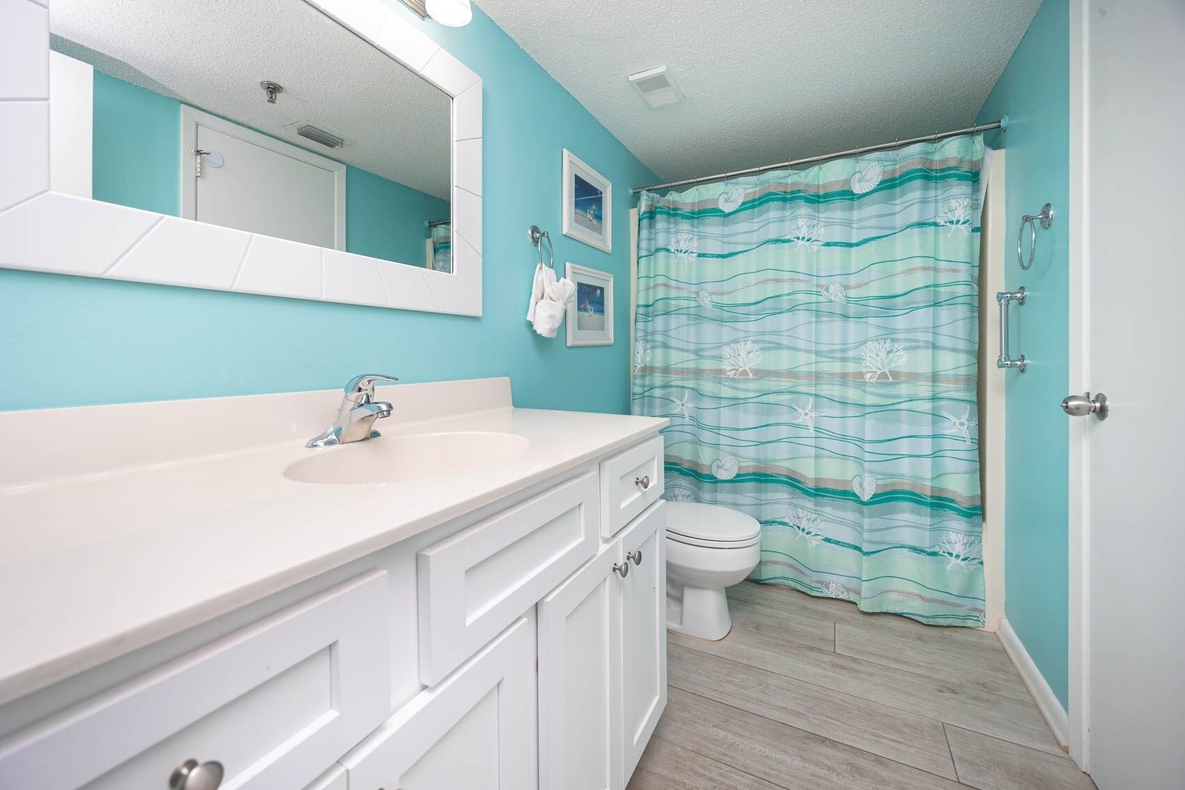 A bathroom with a sink, mirror, toilet, and a shower curtain.