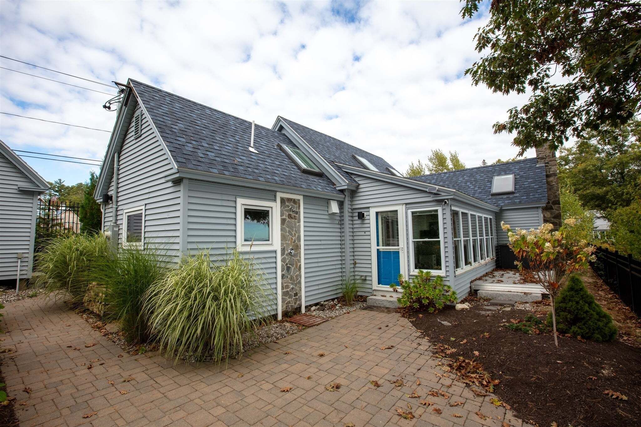 A single-story house with a gabled roof, a front porch, and a small garden area.