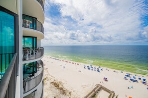 Um hotel na praia com varandas, uma praia de areia e o oceano.