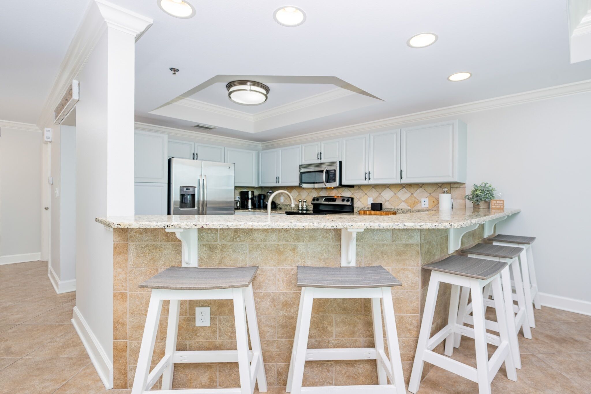 A kitchen with a central island, white cabinets, and a microwave.