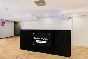 Un comptoir d’accueil avec une pancarte indiquant « TOWNHOUSE, services d’entreprise », situé dans un intérieur moderne avec un plancher en bois et des murs blancs.