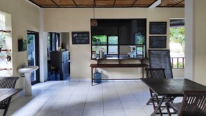 Una cafetería con techo de madera, dispensador de agua, lavamanos y un cartel con el menú.