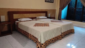 Una cama doble con edredón estampado de leopardo, cabecera de madera, mesita de noche con lámpara y ventana con cortinas.