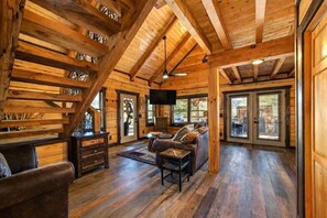 A log cabin interior with a wooden staircase, a sofa, a television, and a fireplace. - Makin' Memories 2 Bedroom Cabin (Sevierville)