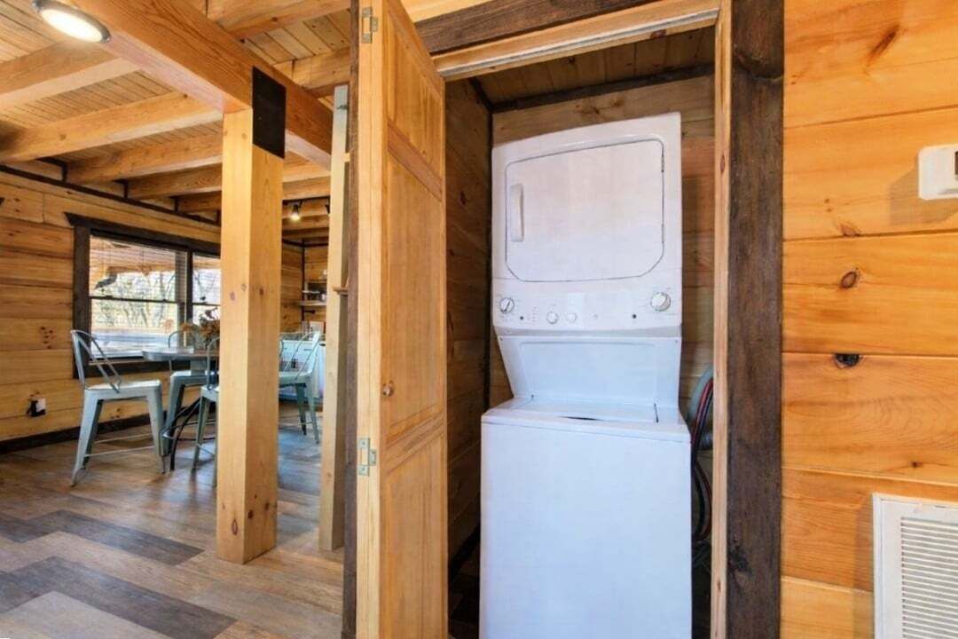 A compact room with a wooden interior, a white appliance, and a dining area with chairs and a table.