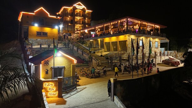 Un hotel de varios pisos con una entrada bien iluminada, un área de estar al aire libre y una escalera que conduce a los pisos superiores.