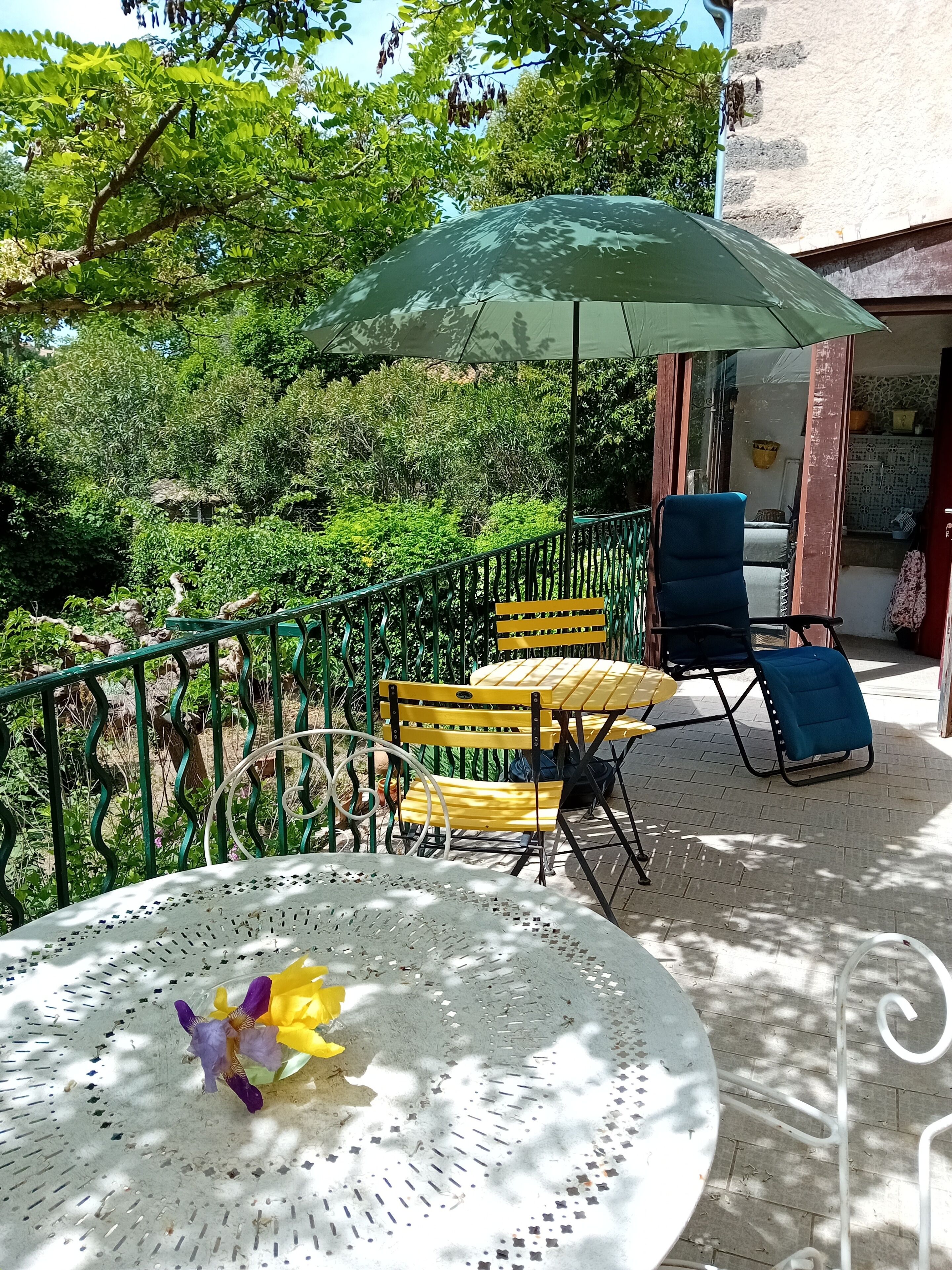 Een terras met een tafel, stoelen en een parasol.