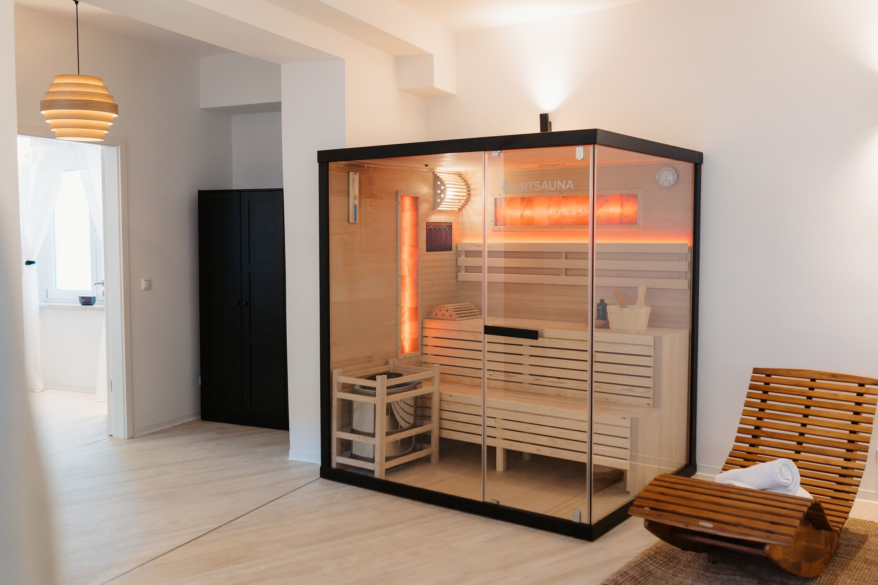 Un sauna avec une enceinte en verre, des bancs en bois et une serviette posée sur un banc.