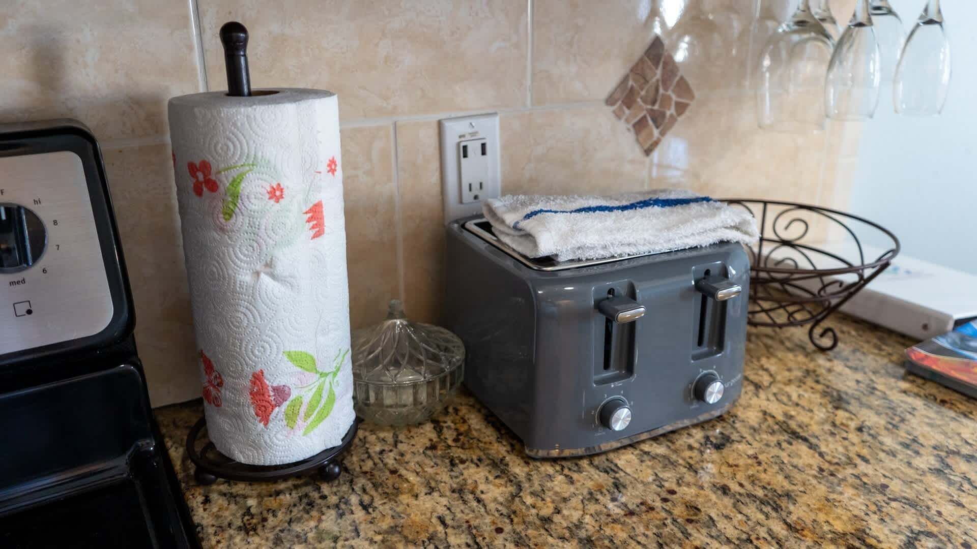 Una cocina con un dispensador de toallas de papel, un tostador y un frasco de vidrio sobre una encimera de granito.