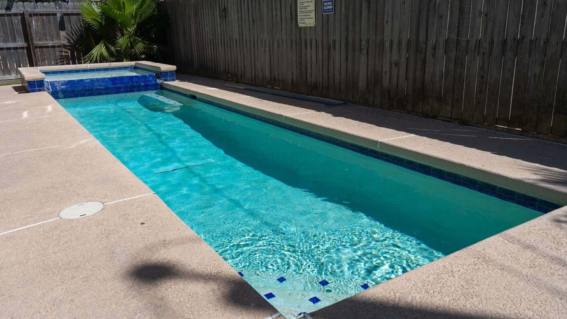 Una piscina rectangular con borde de azulejos, rodeada por una solería de hormigón.