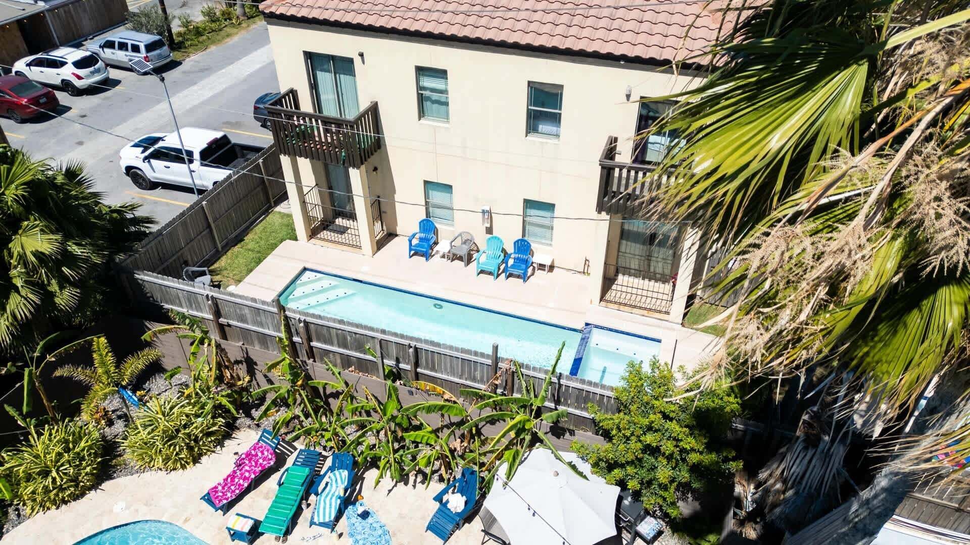 Edificio residencial con piscina, varios balcones y vista a coches estacionados.