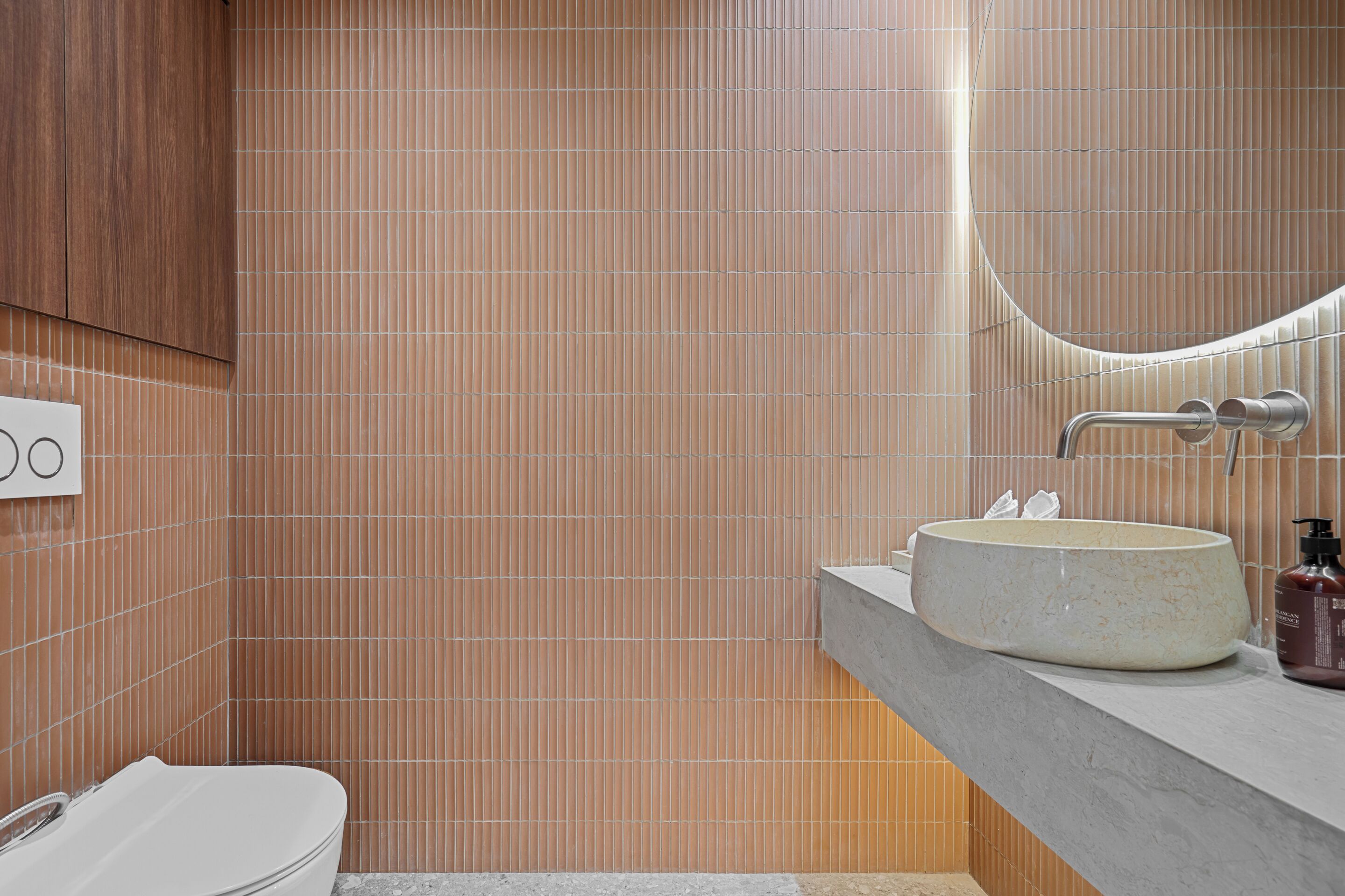 A modern bathroom with a large sink, a mirror, and a toilet.