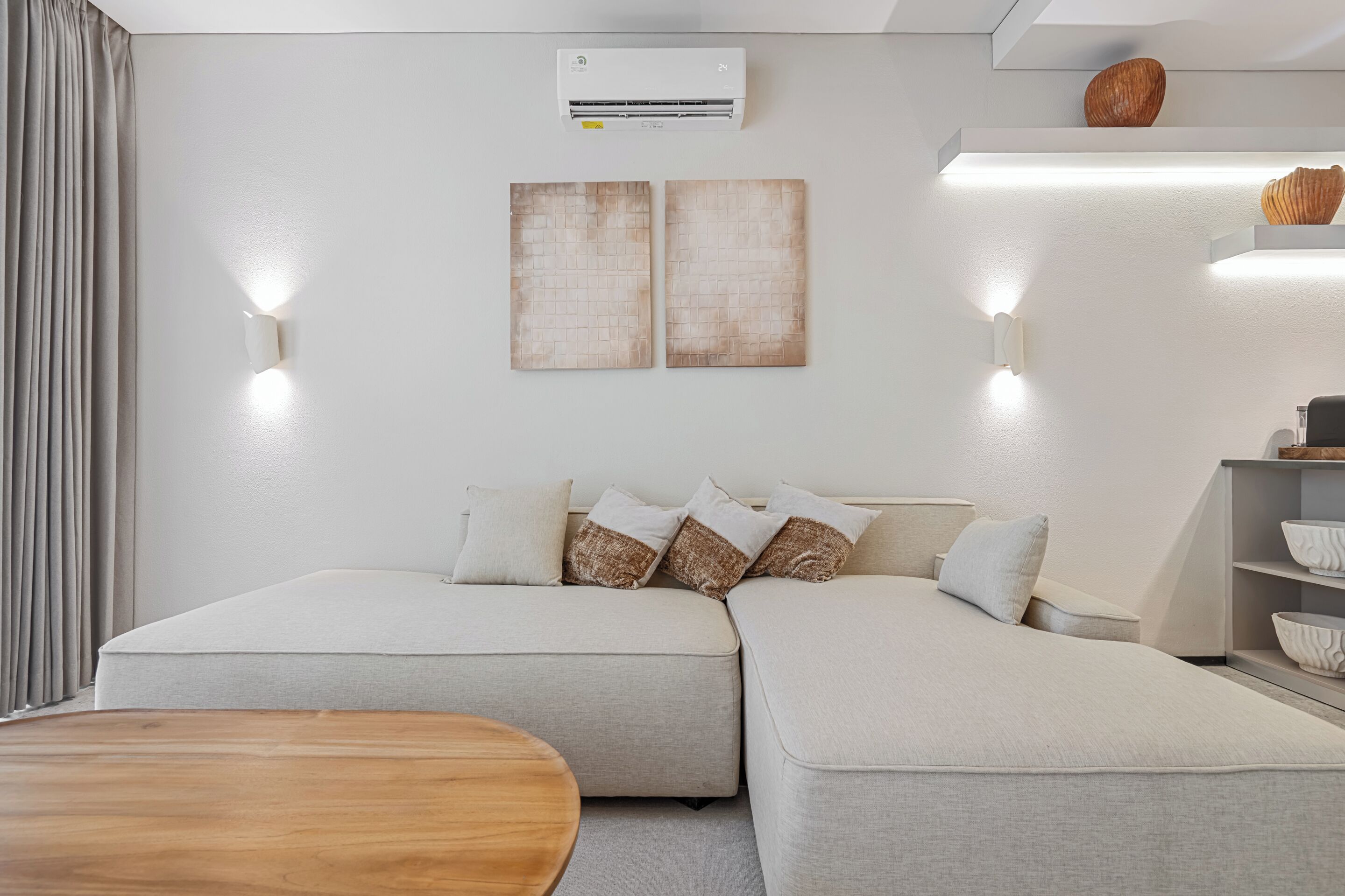 A modern room with a sofa, a wooden table, and wall-mounted lighting.