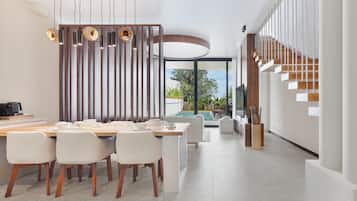 Un comedor moderno con una mesa de madera, sillas blancas e iluminación colgante.