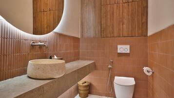 A modern bathroom with a round sink, a mirror, and a toilet.