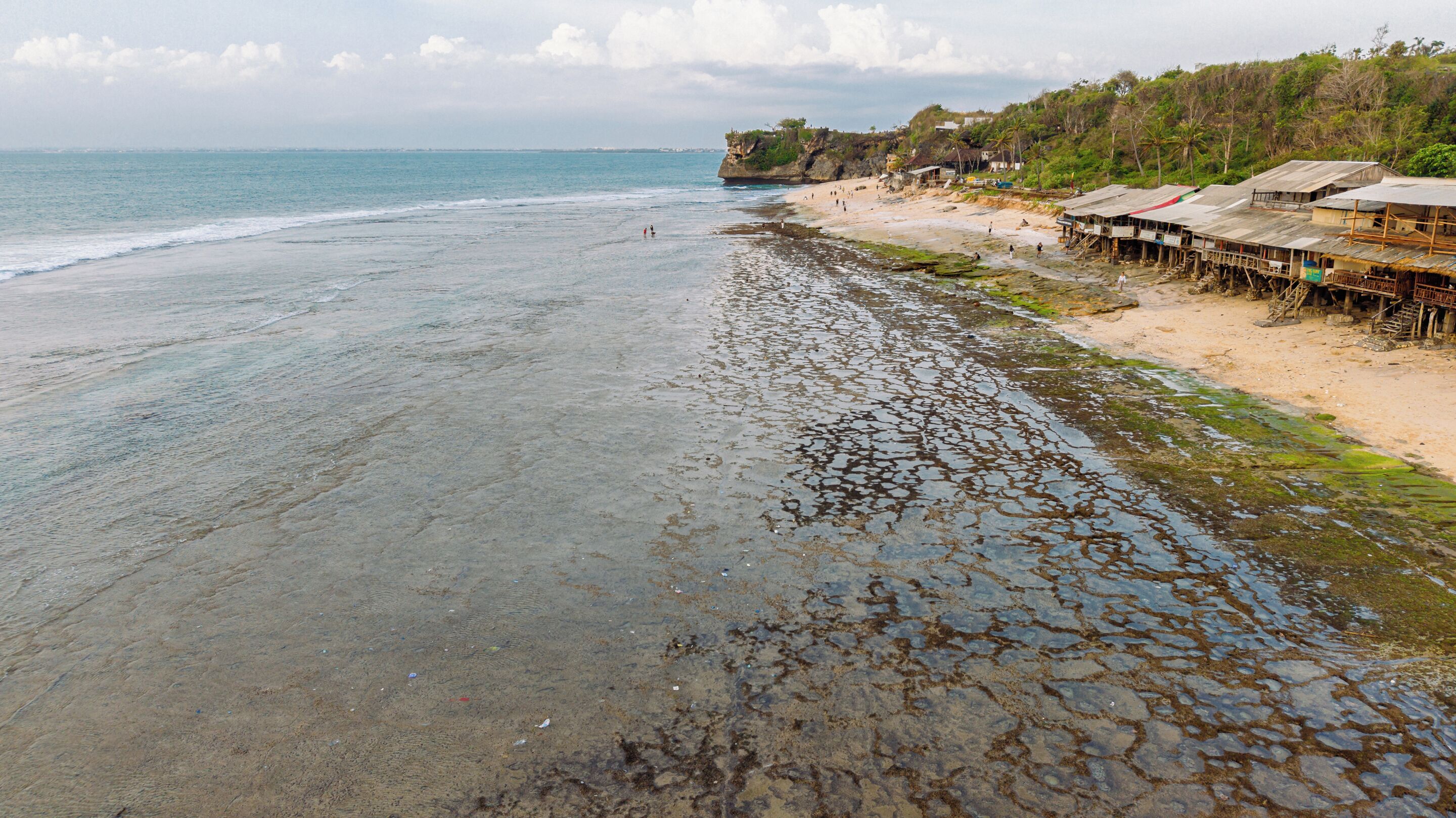 A beach with a rocky shoreline, a sandy beach, and wooden structures on stilts.