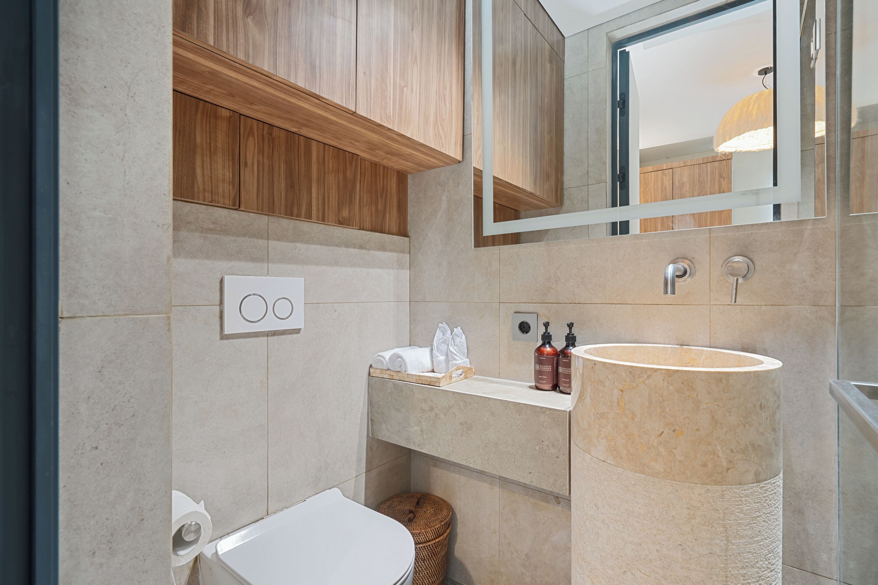 A modern bathroom with a wooden vanity, a large sink, and a mirror.