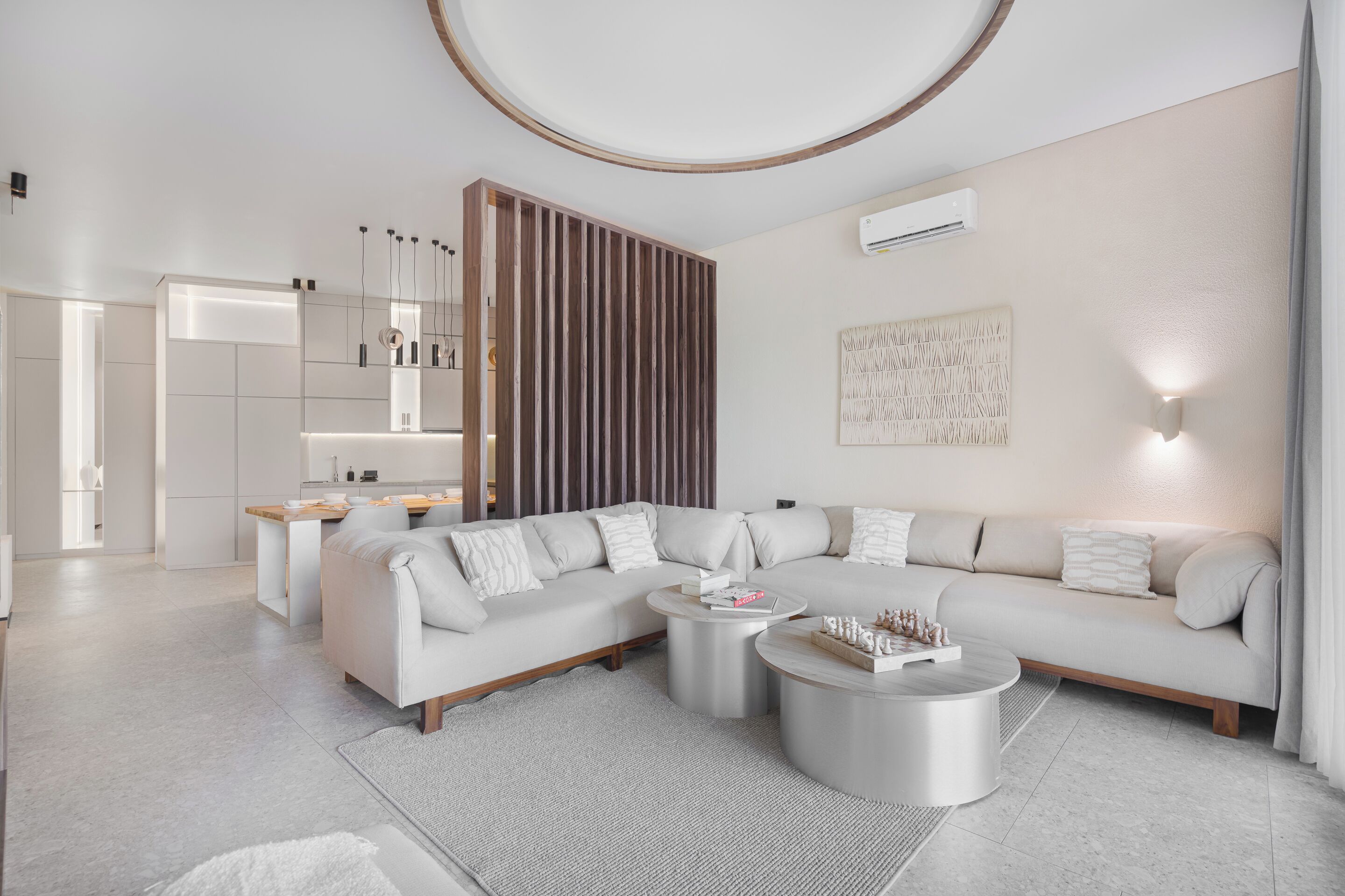 A modern living room with a sectional sofa, two round coffee tables, and a kitchen area in the background.