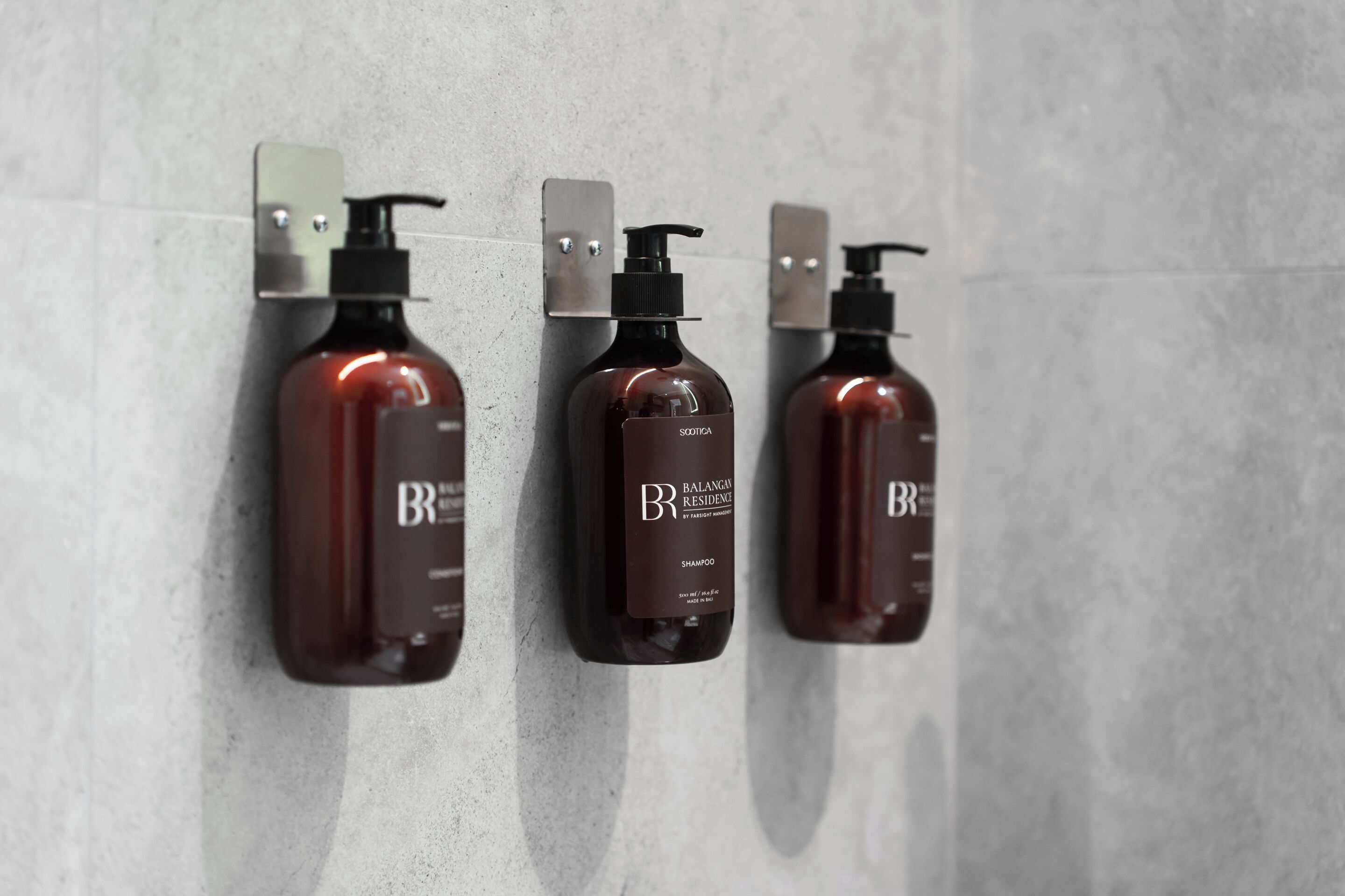 Three bottles of shampoo mounted on a wall.