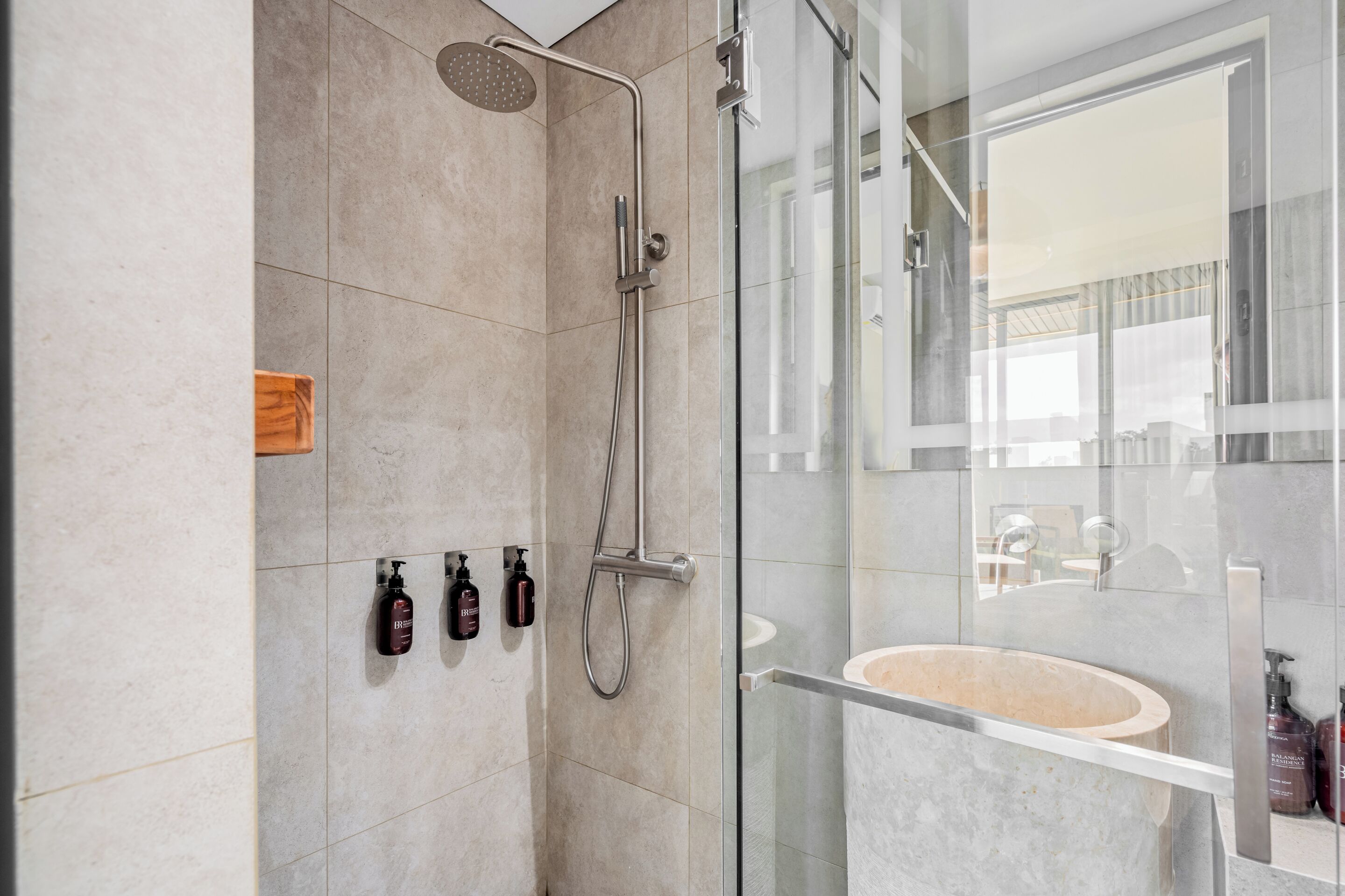 Une salle de bain moderne avec une douche à l’italienne en verre, un lavabo en marbre et une porte de douche en verre.