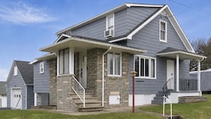 A two-story house with a front porch, stone foundation, and a small front yard. - Johnstown Stay Near Laurel Highlands & Hiking (Johnstown)