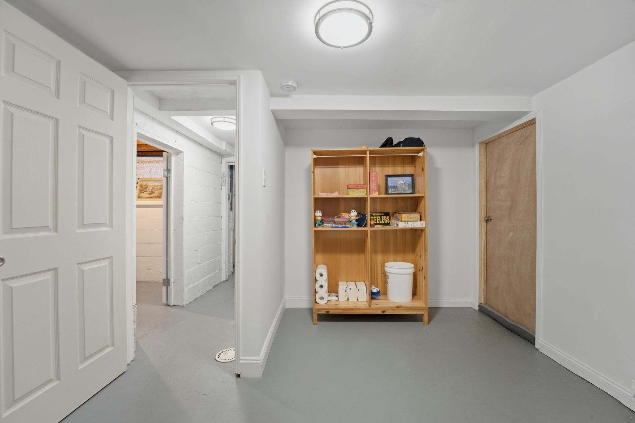 A hallway with a wooden bookshelf, a white door, and a wooden door on the right.